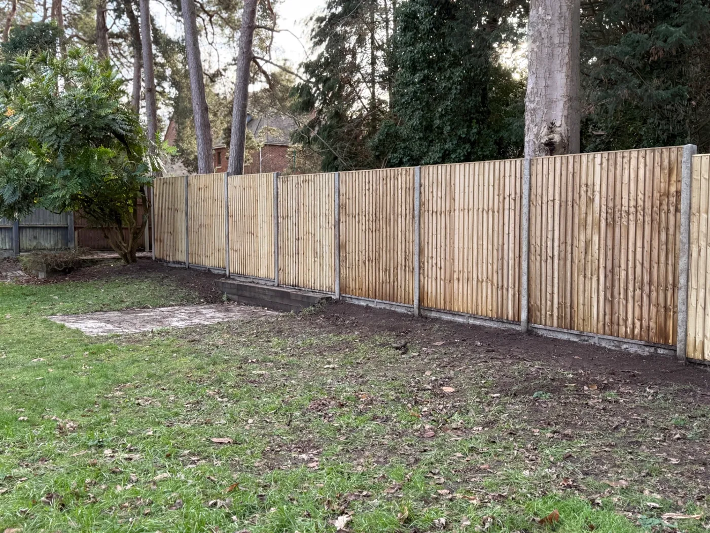 Long run of closeboard fencing installed at the edge of woodland near Haslemere