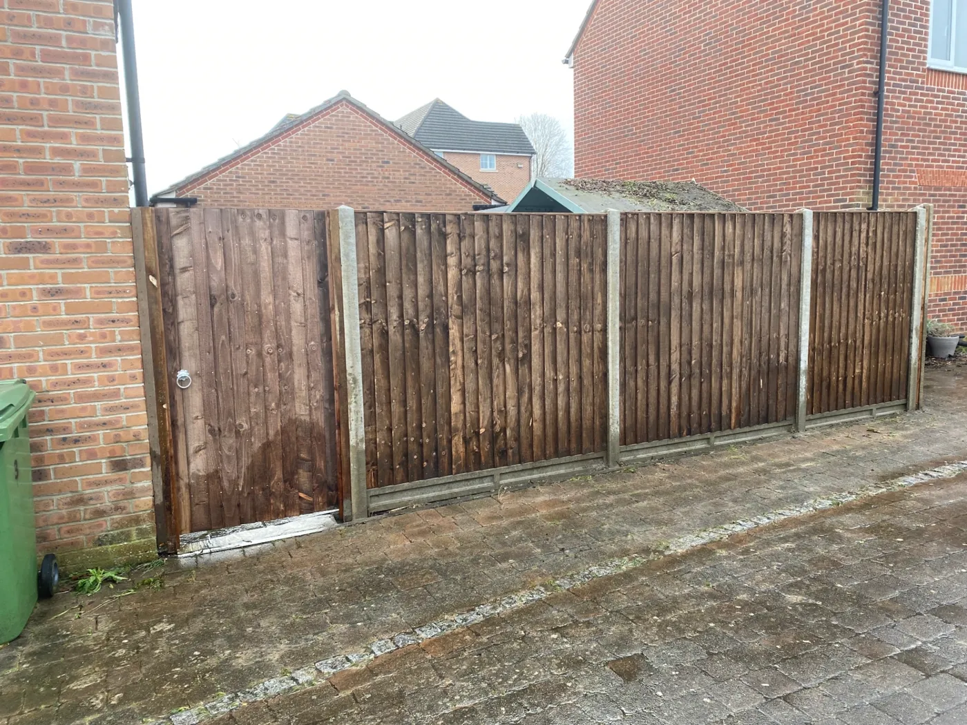 Fence panels and matching side gate installed on a paved driveway in Haslemere