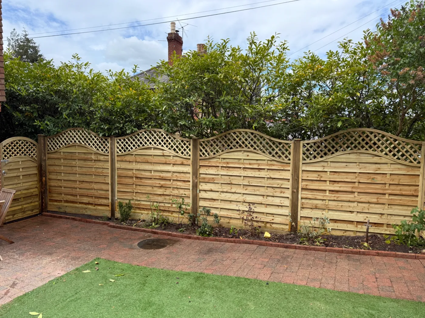 Wavy trellis topped garden fence panels fitted along a Haslemere patio